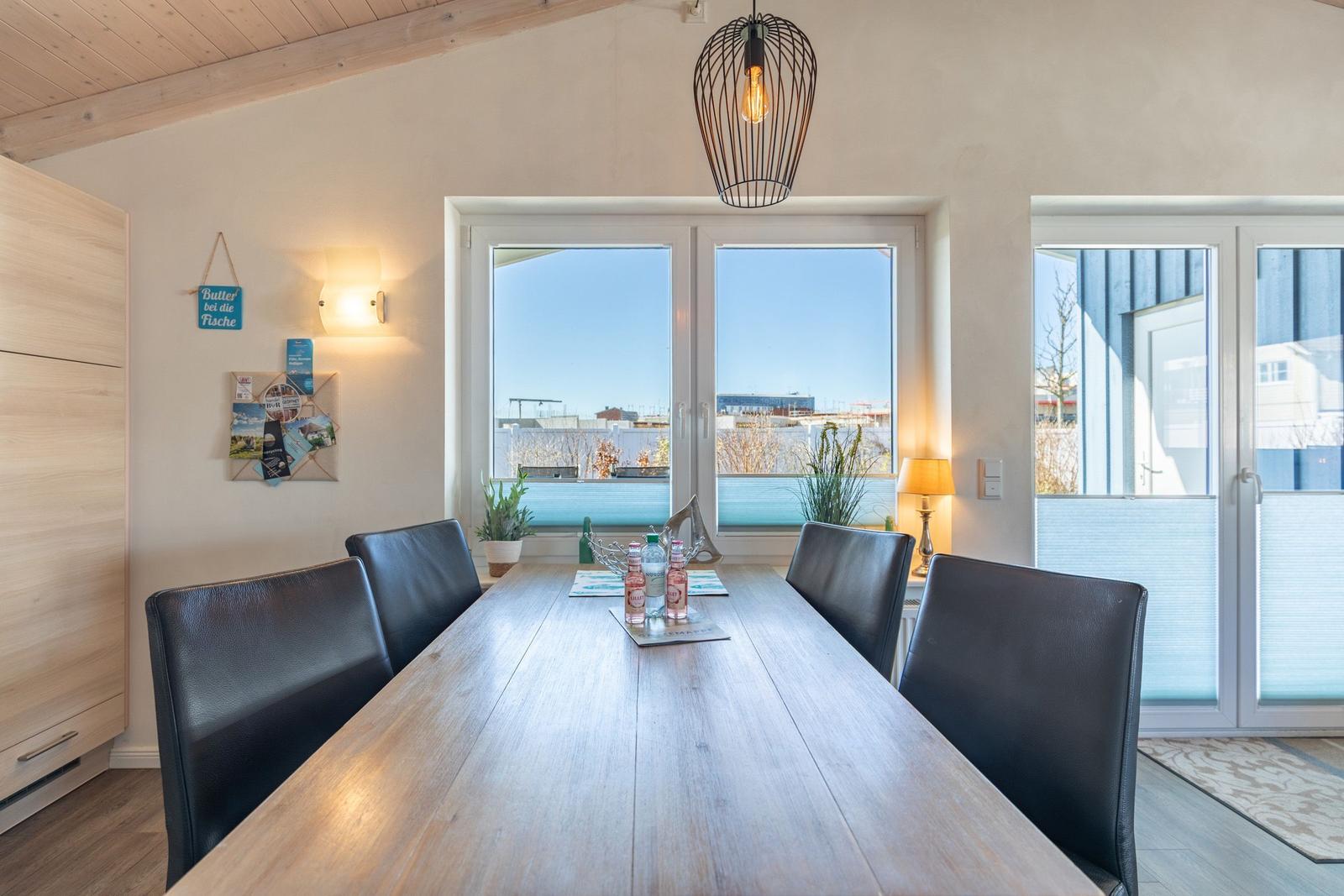 Esszimmer mit langem Holztisch, schwarzen Stühlen und Fensterblick auf Außenbereich.