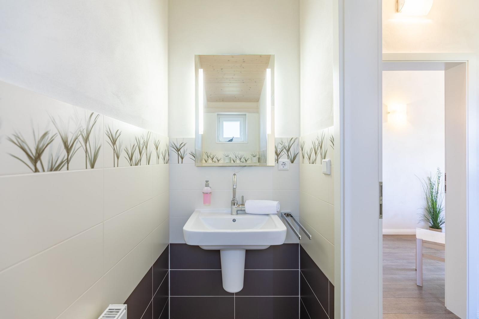 Badezimmer mit Waschbecken, Spiegel und Pflanzenmotivfliesen
