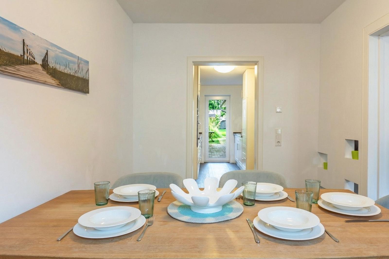 Esstisch mit vier Plätzen, weißer Schale und Bild an der Wand.