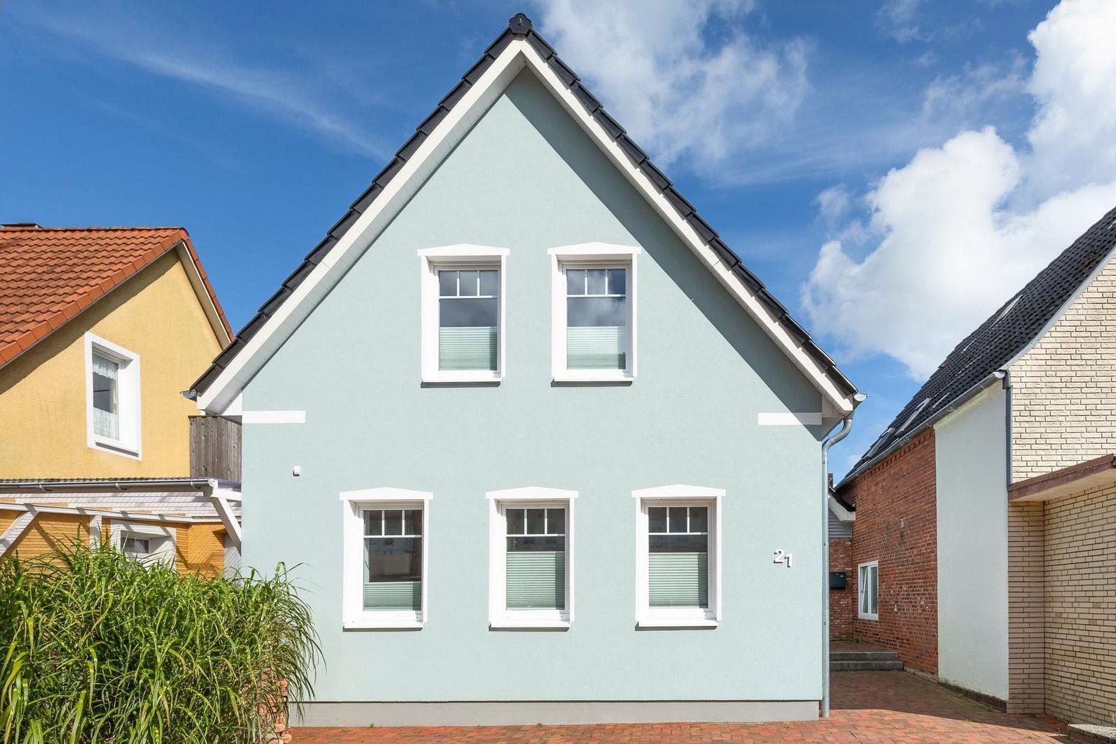 Ein zweistöckiges Haus mit hellblauer Fassade und weißen Fensterrahmen.