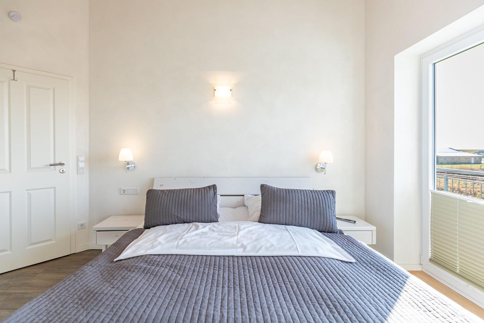Schlafzimmer mit Bett, Nachttischen und Fenster zur Aussicht.