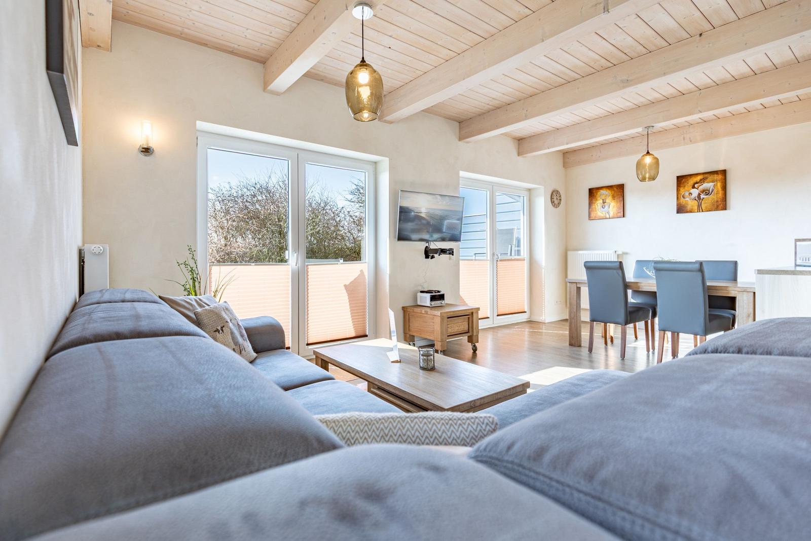Wohn- und Essbereich mit Sofa, Esstisch und Holzbalkendecke.
