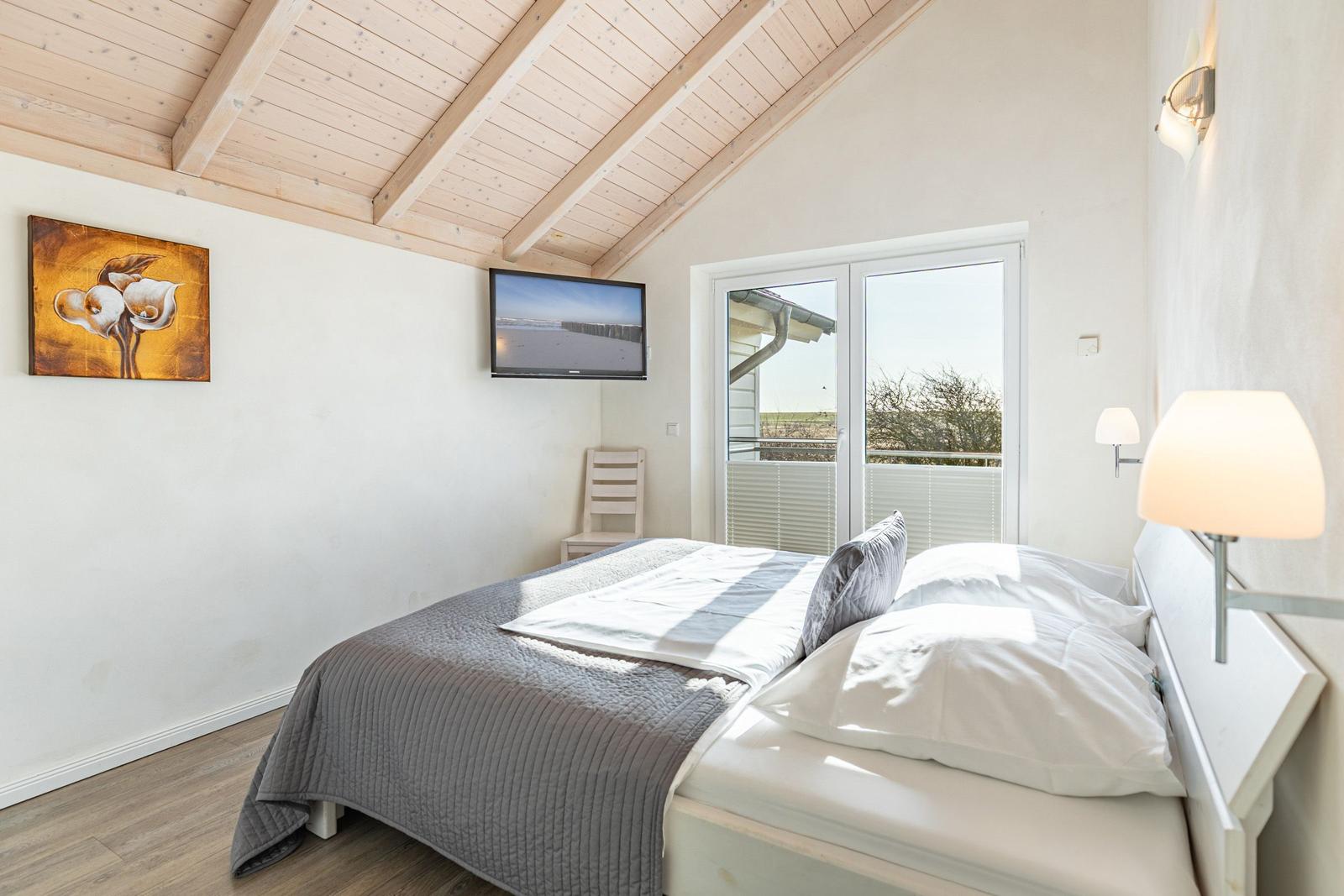 Schlafzimmer mit Bett, TV und Balkonansicht.