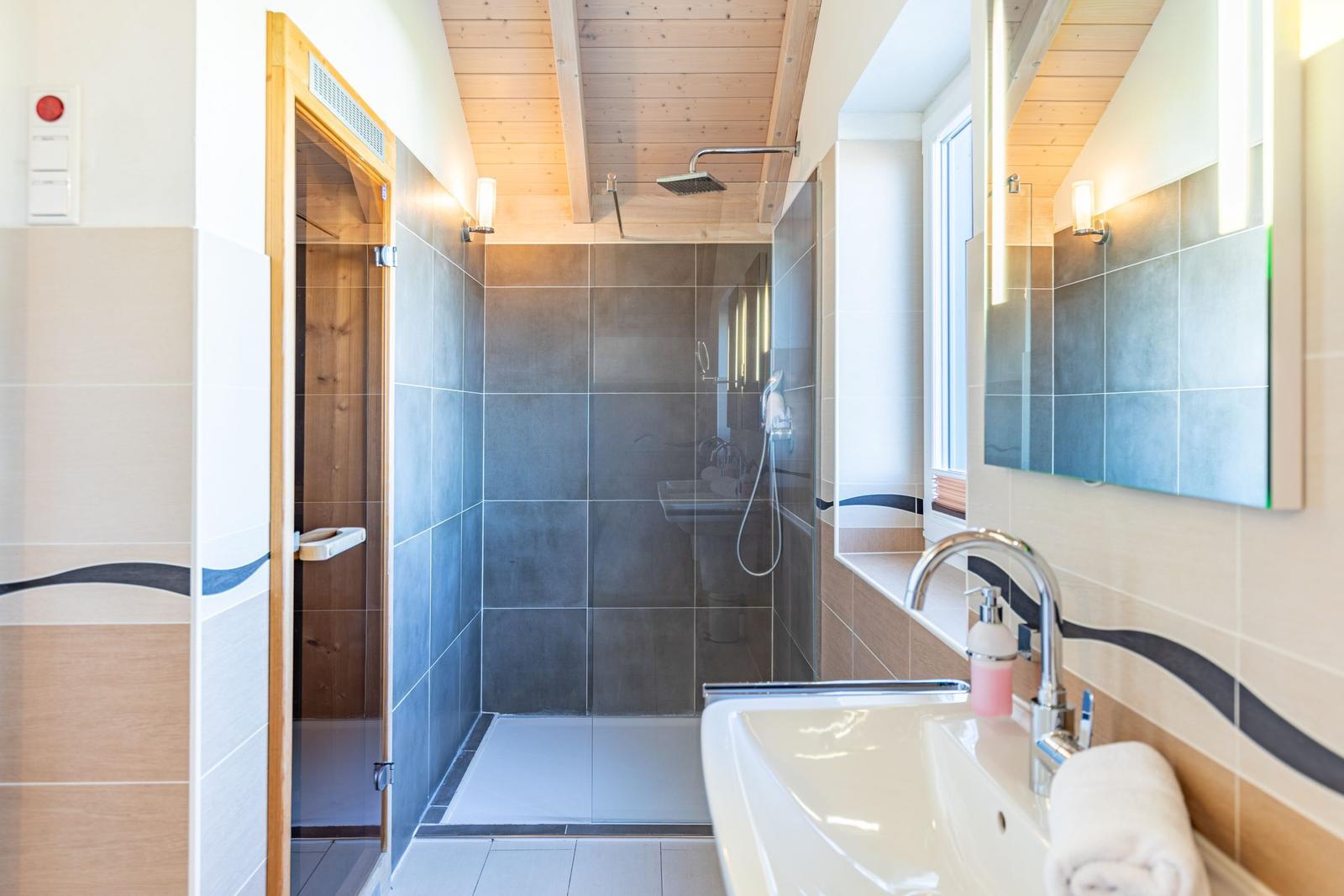 Badezimmer mit Dusche, Waschbecken und Sauna.