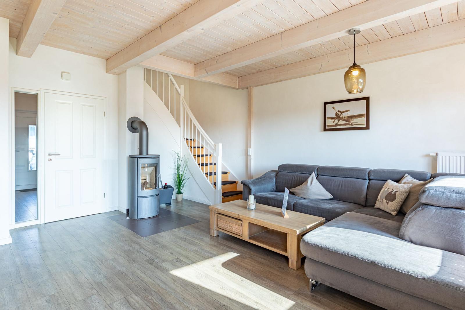 Wohnzimmer mit Sofa, Kamin und Treppe zur oberen Etage.