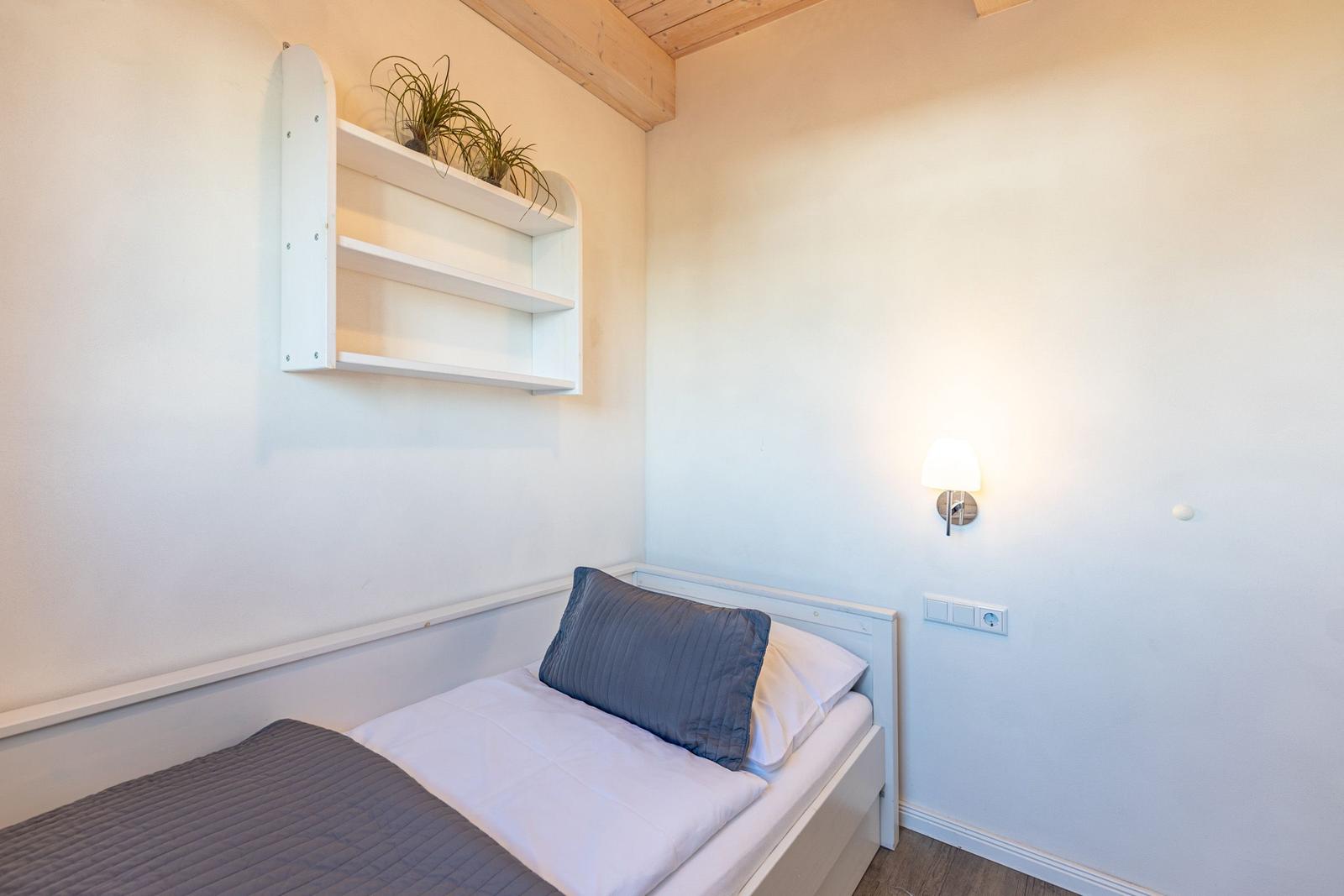 Ein Schlafzimmer mit Bett, Wandregal und Stehlampe.