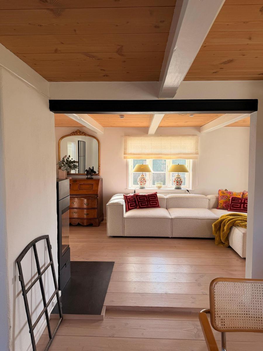 Wohnzimmer mit Sofa, Fenster, Lampe und Holzboden