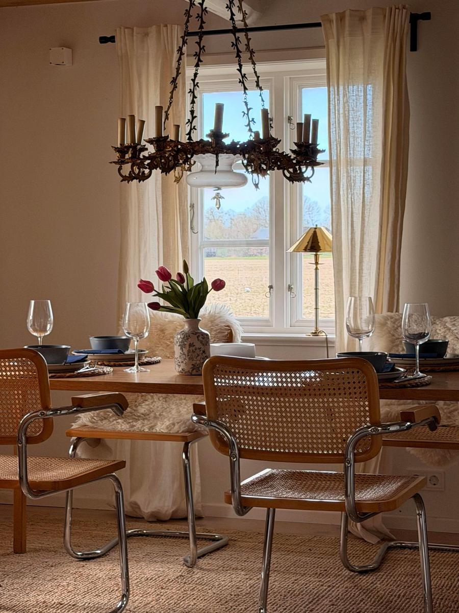 Esszimmer mit Holztisch, Stühlen und Fensterblick auf Feld.