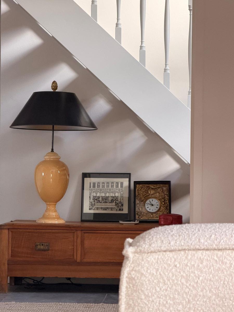 Unter der Treppe steht ein Holzschrank mit Lampe, Bild und Uhr.
