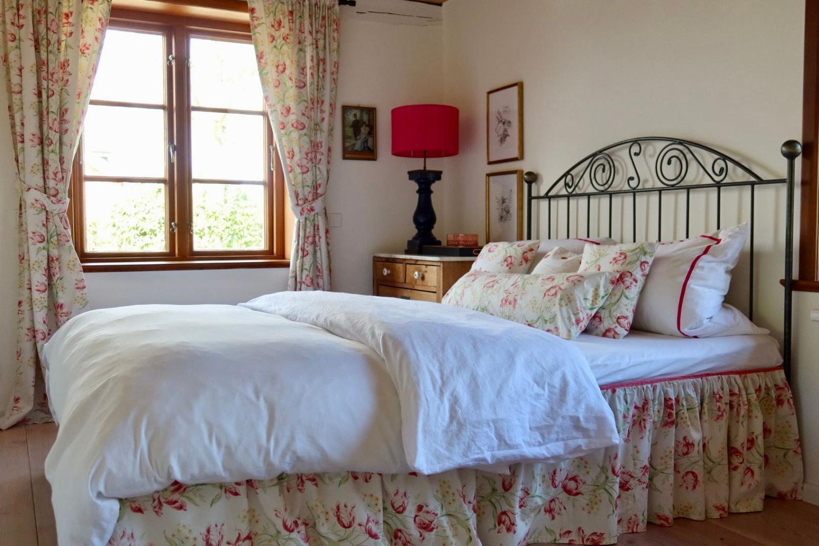 Schlafzimmer mit Bett, Fenster und Nachttisch.