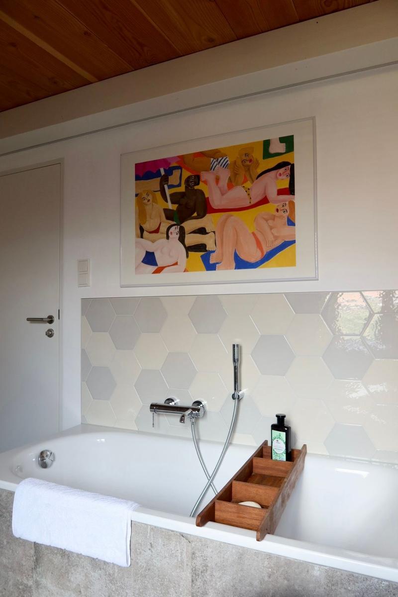 Bad mit Badewanne, sechseckigen Fliesen und Wandbild.