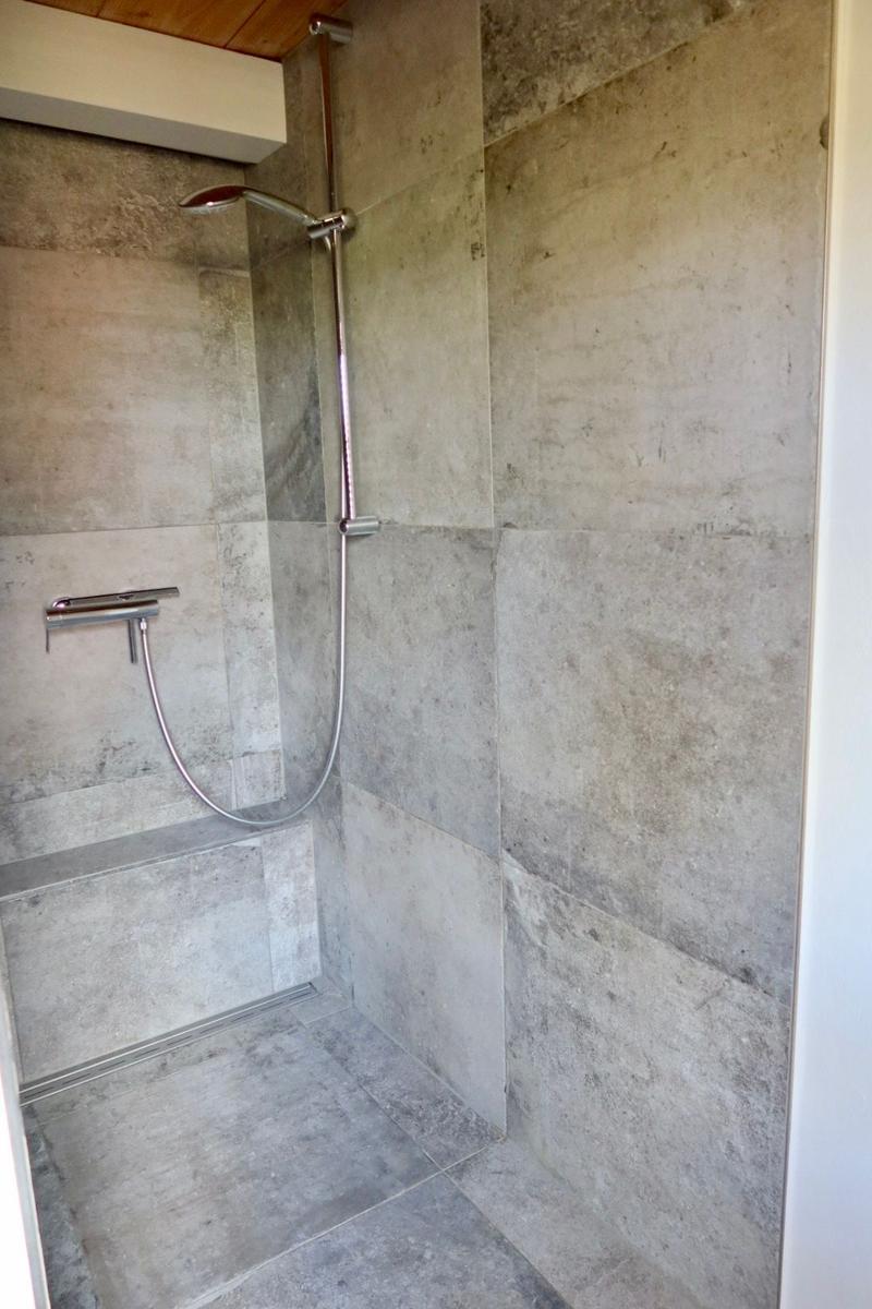 Duschkabine mit Duschbrause und Handbrause, Wand- und Bodenfliesen aus Stein