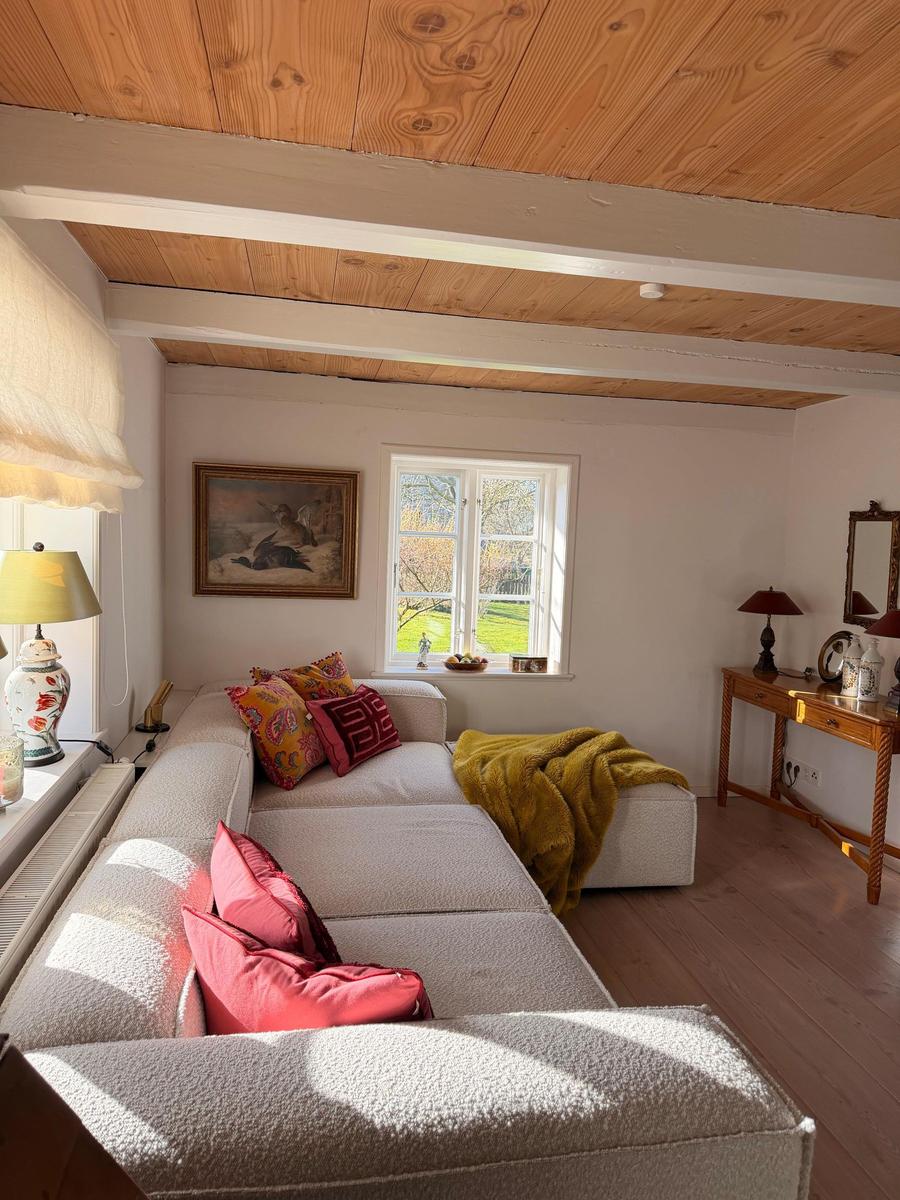 Wohnzimmer mit Sofa, Fenster und Holzdecke.