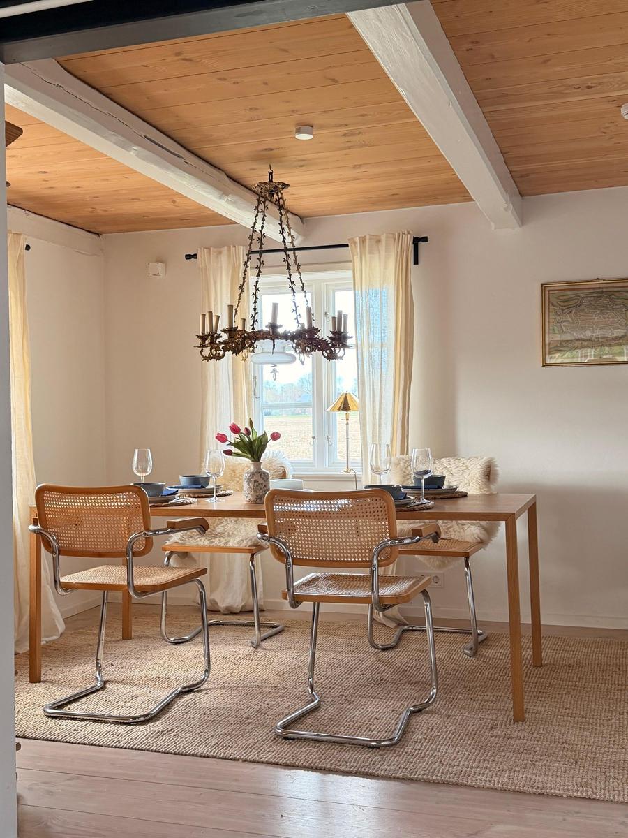 Esszimmer mit Holztisch, vier Stühlen und Kronleuchter unter Holzdecke.