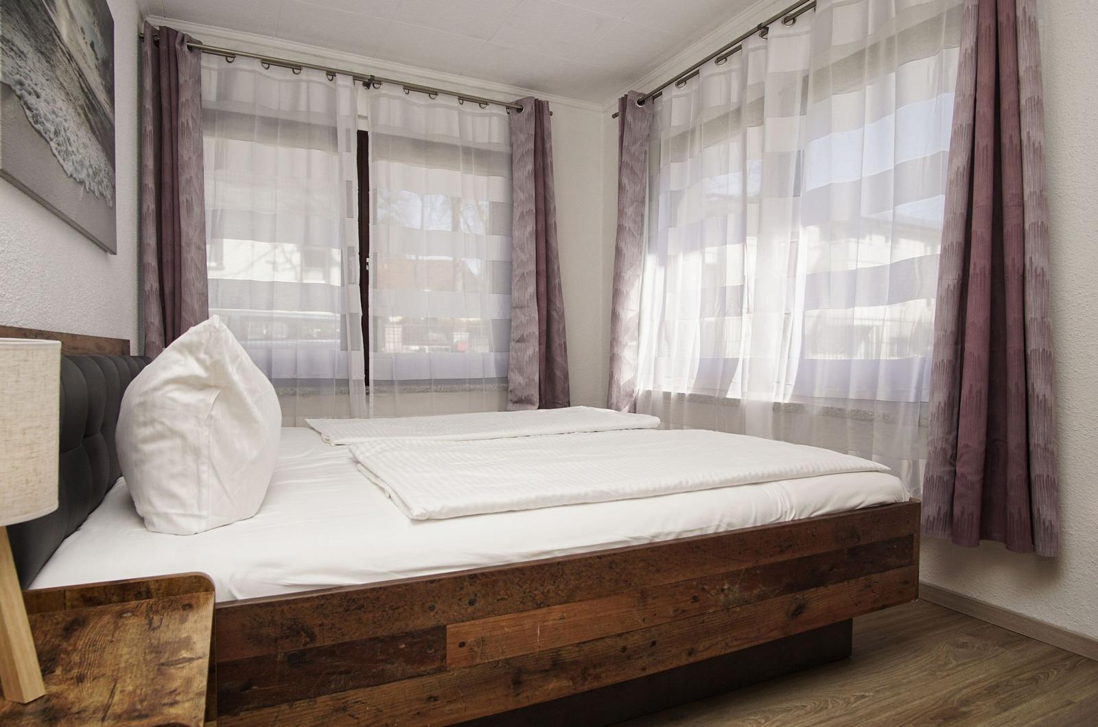 Schlafzimmer mit Bett, Vorhängen und Wandbild
