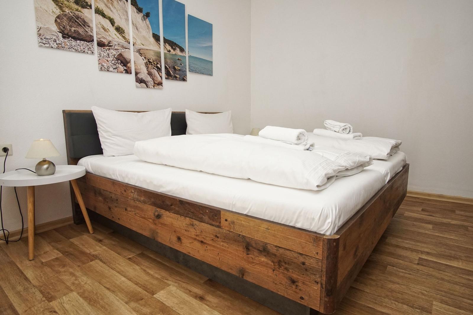 Schlafzimmer mit Holzbett, weißen Bettwäsche und Wandbildern an der Wand.
