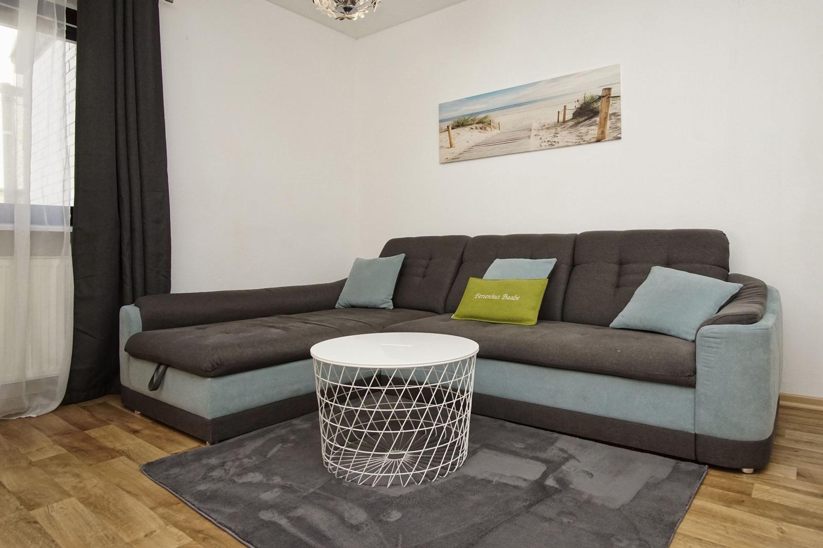 Ein Wohnzimmer mit einem Ecksofa, einem runden Tisch und einem Wandbild.