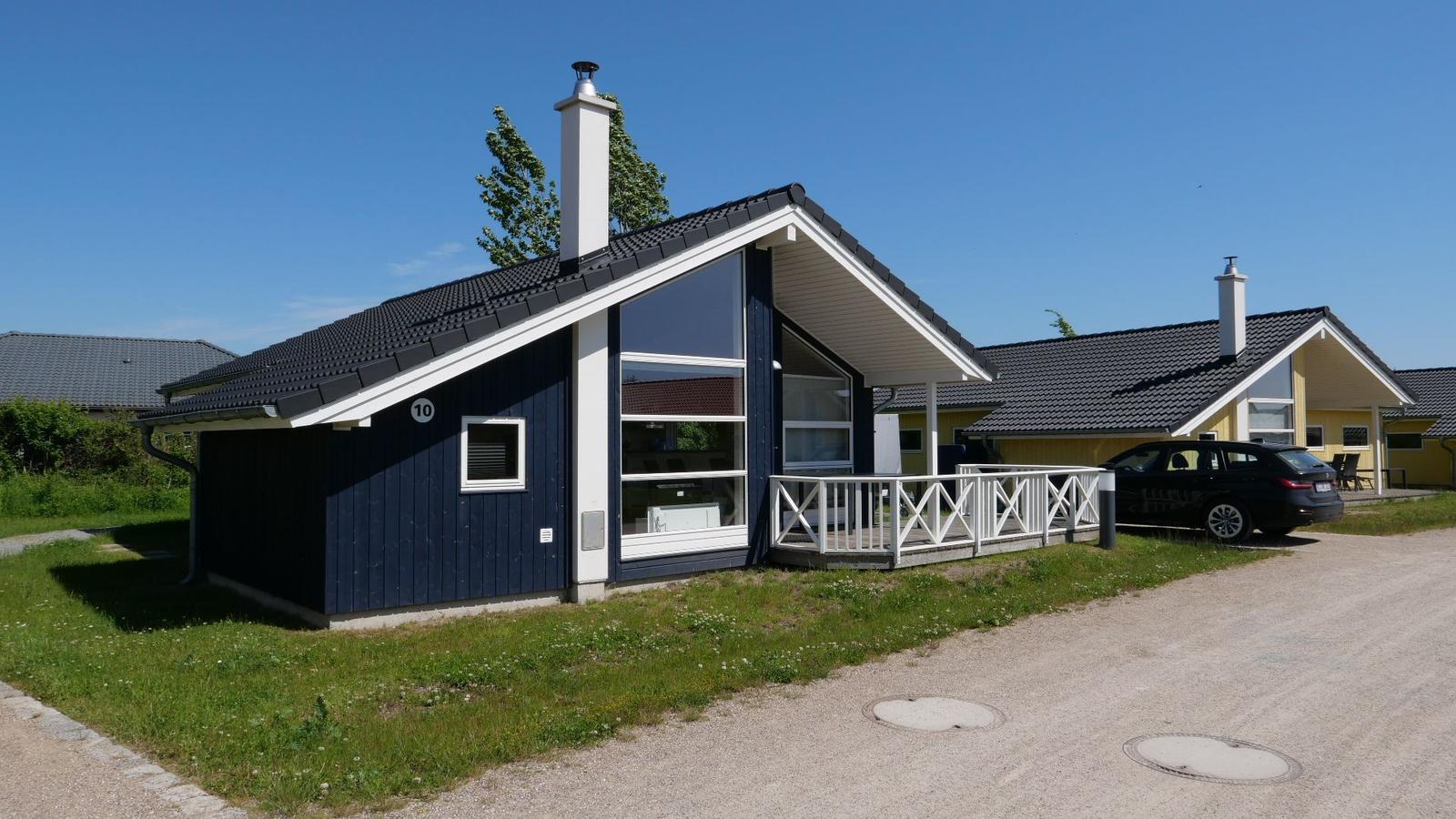 Blau gestrichenes Ferienhaus mit weißem Balkon und Dachreiter. Nebenhaus ist gelb.