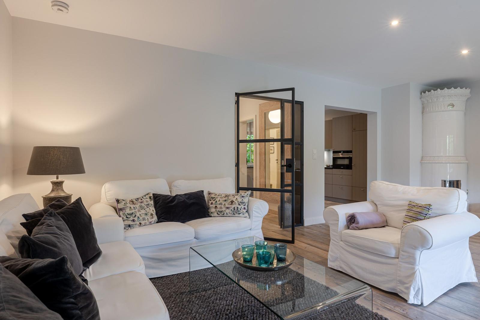 Wohnzimmer mit weißen Sofas, Glas-Tisch und Kamin