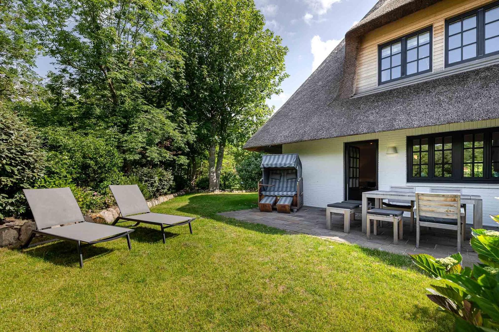 Haus mit Dachstuhl, Garten, Liegen und Tisch mit Stühlen