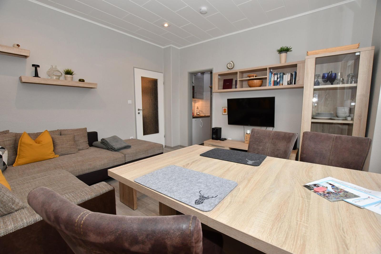 Wohn- und Essbereich mit Sofa, Esstisch und Fernseher.