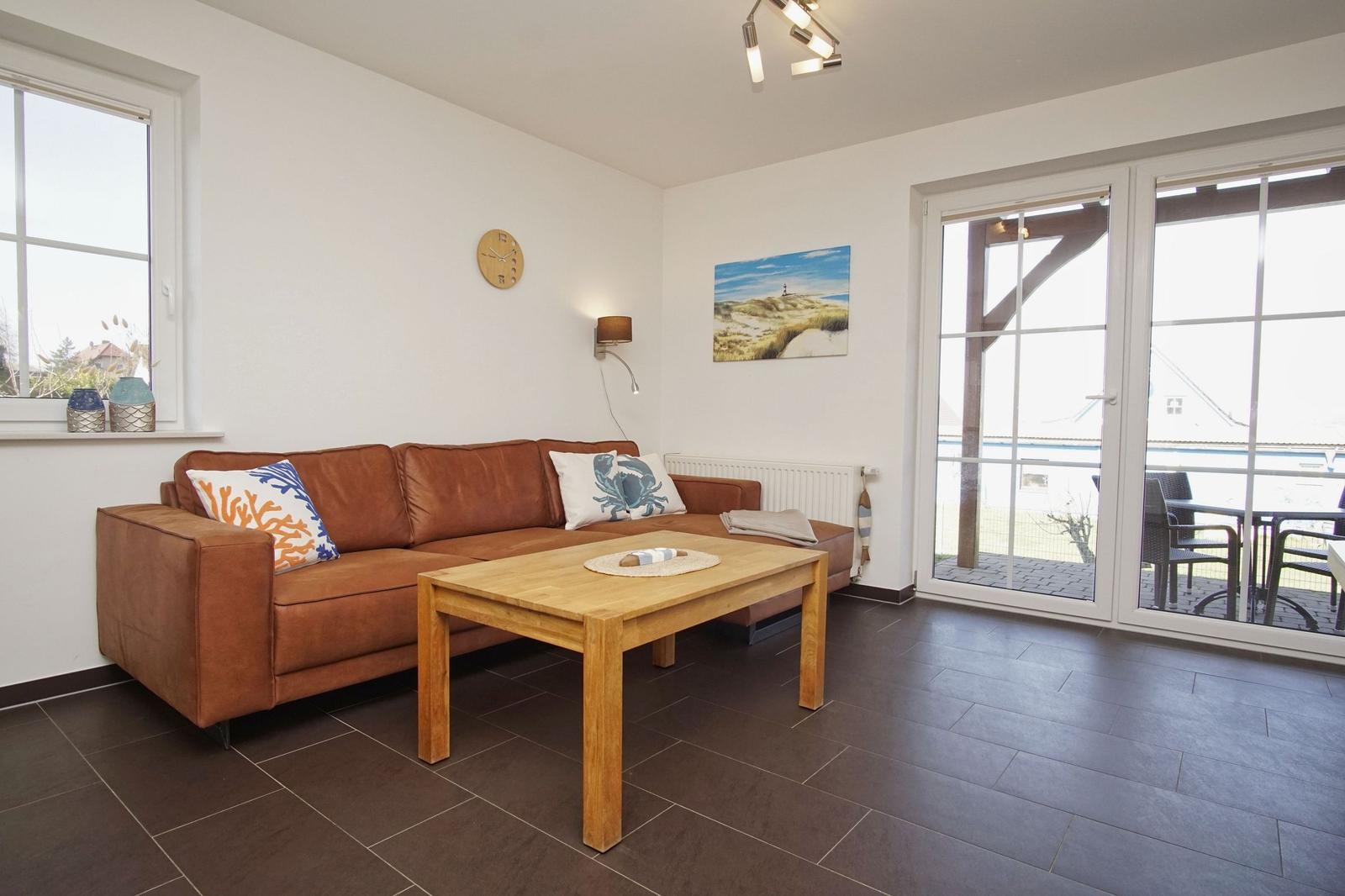 Wohnzimmer mit braunem Sofa, Holztisch und Blick auf Balkon.