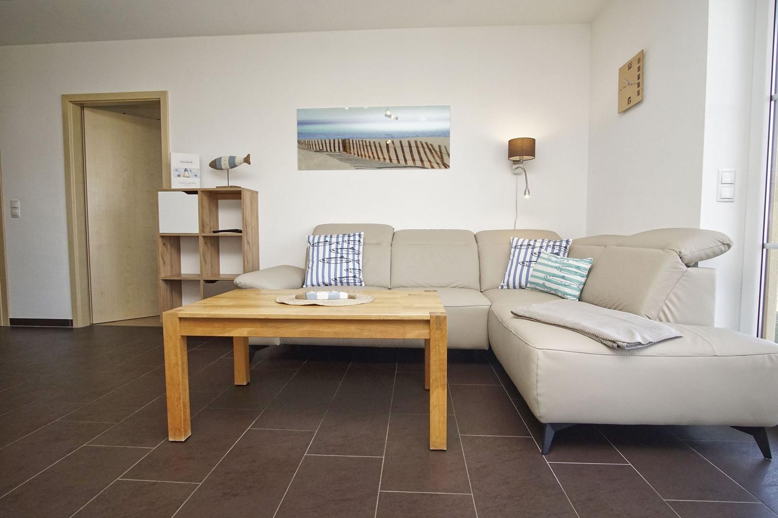 Ein Wohnzimmer mit einem hellen Sofa, einem Holztisch und einer Wanddekoration.