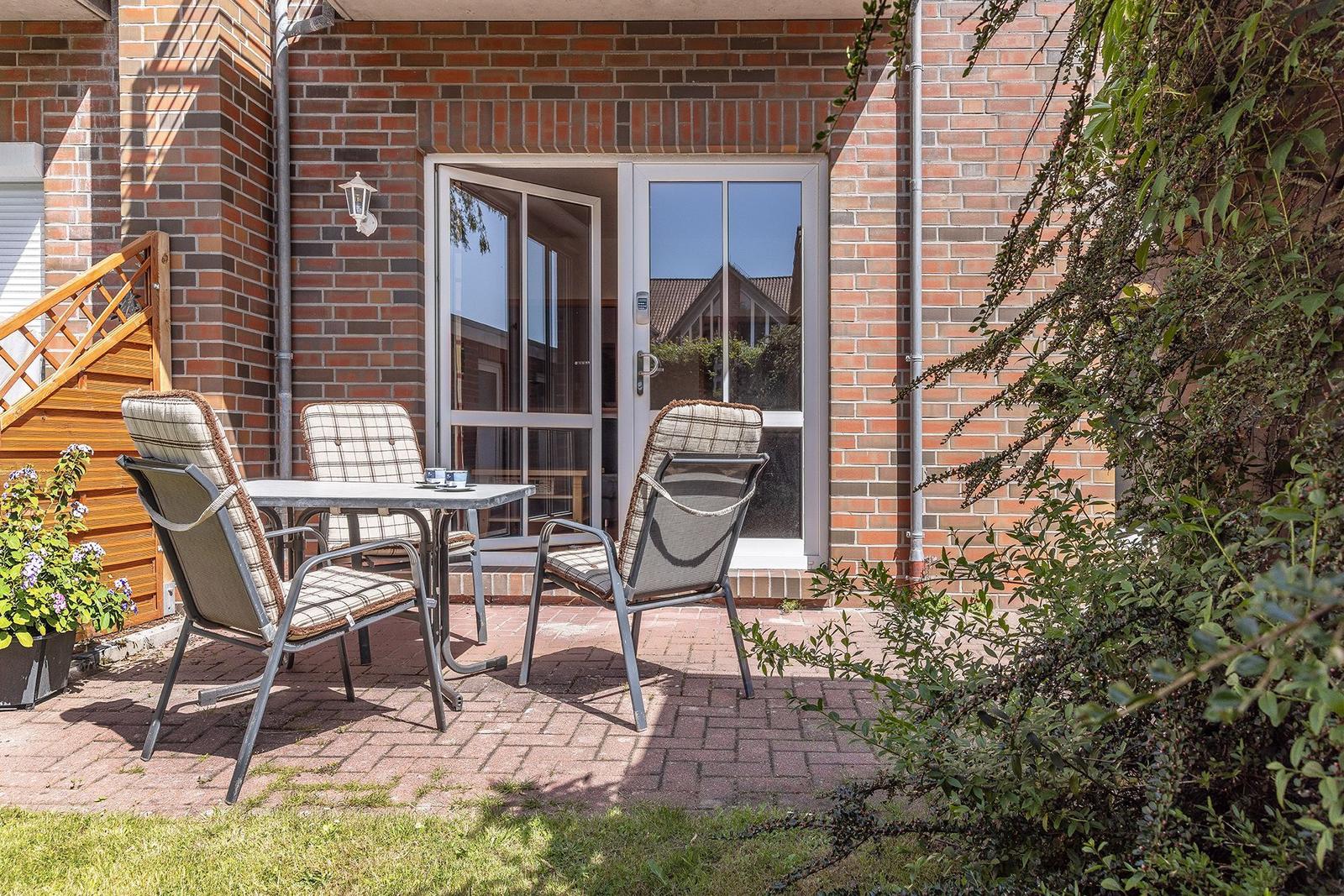 Terrasse mit Tisch und Stühlen vor einer Glastür.