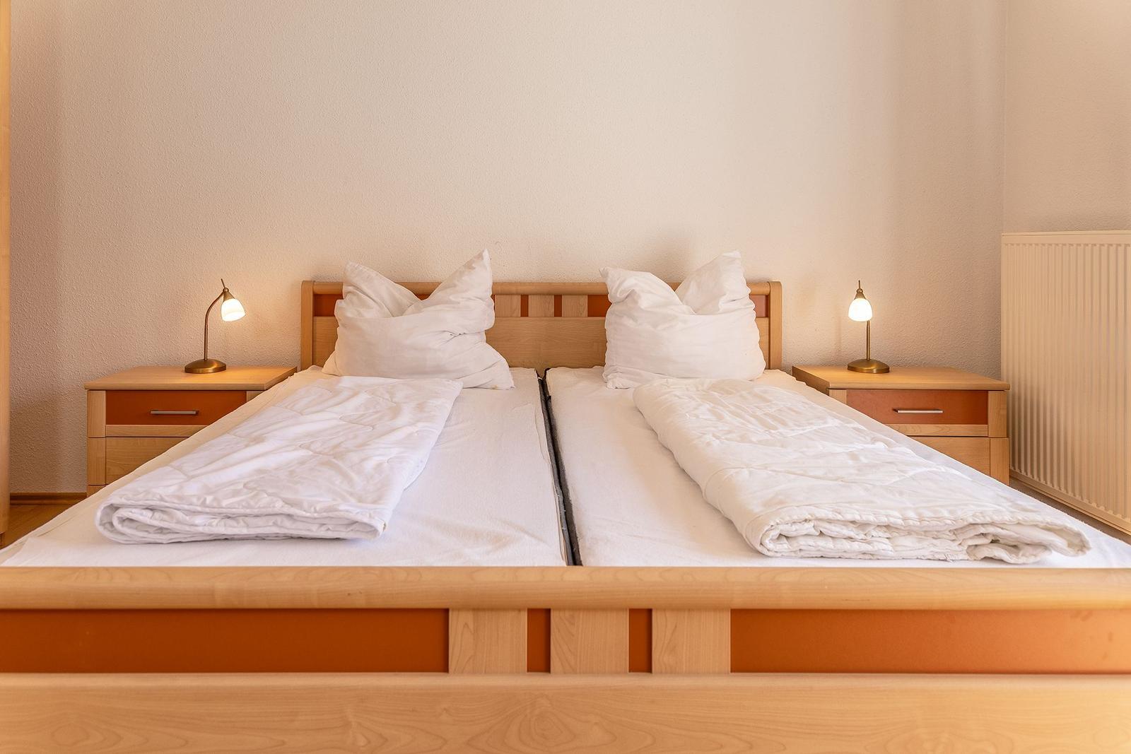 Zwei Betten mit weißen Bettwäsche und Nachttischen mit Lampen.