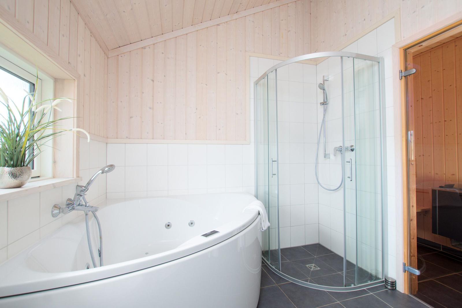 Bad mit Whirlpool, Dusche und Sauna. Holzwände und Fenster mit Pflanze.