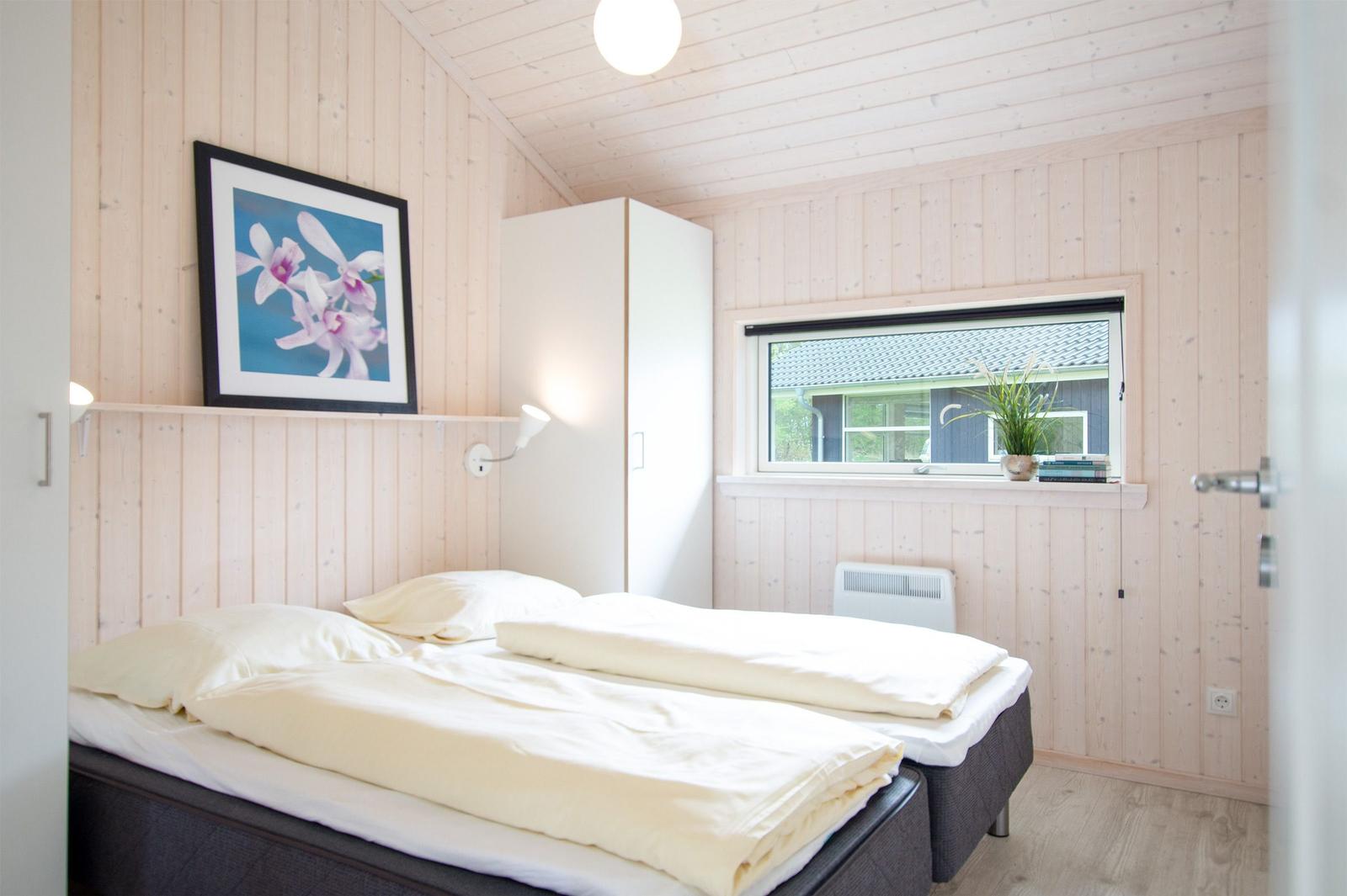 Schlafzimmer mit Doppelbett, Fenster und Wandbild.