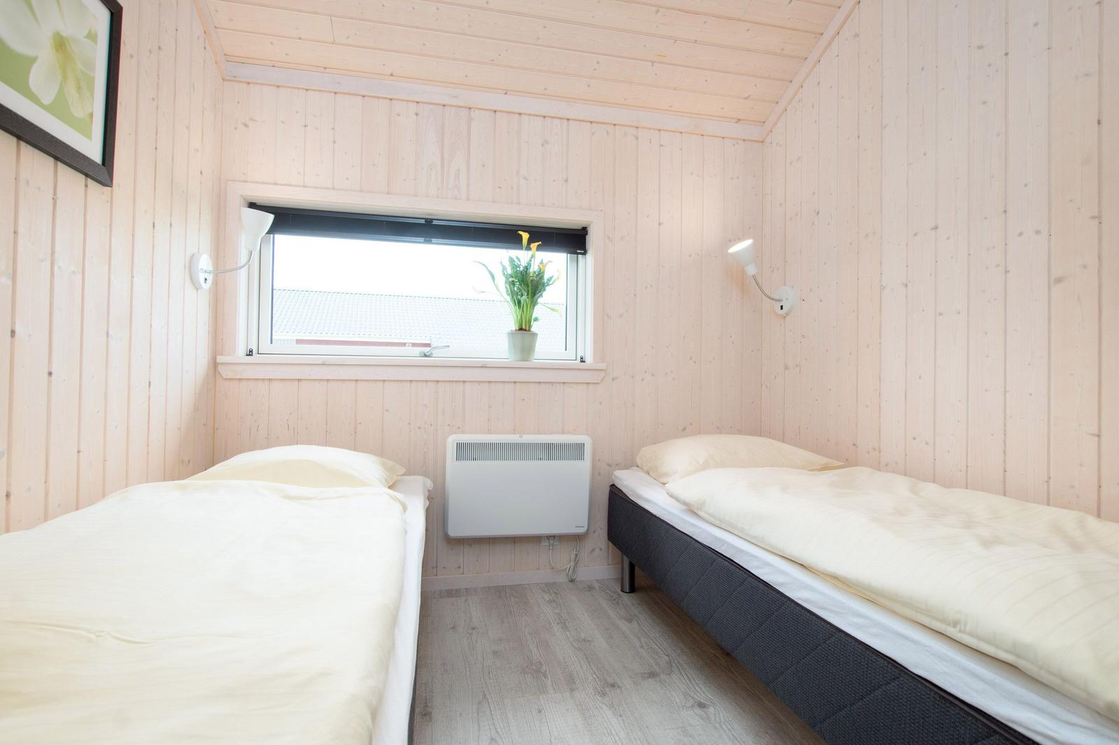 Zwei Betten, Fenster mit Pflanze, Holzwände und Boden.