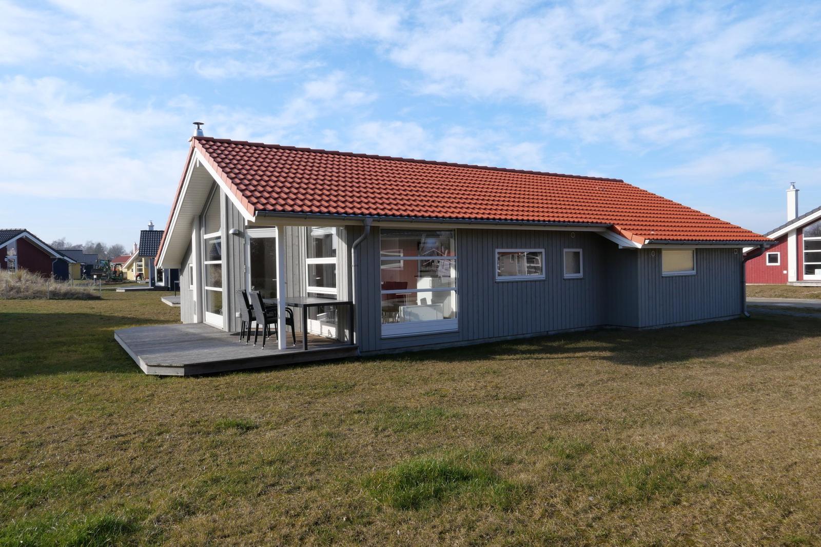 Ein modernes Haus mit rotem Dach und Holzterrasse im Freien.