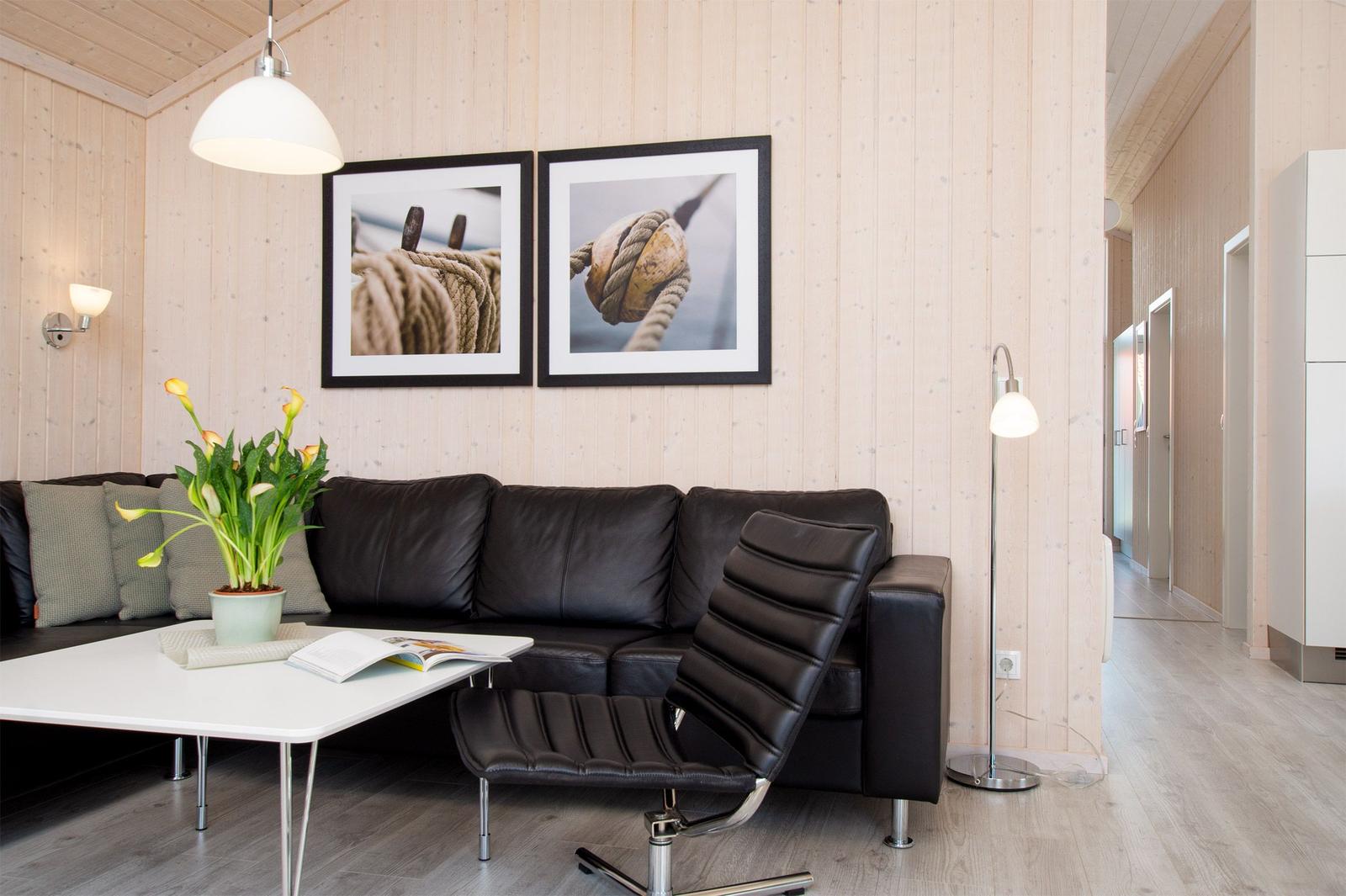 Wohnzimmer mit braunem Sofa, weißen Wänden und zwei Bildern an der Wand.