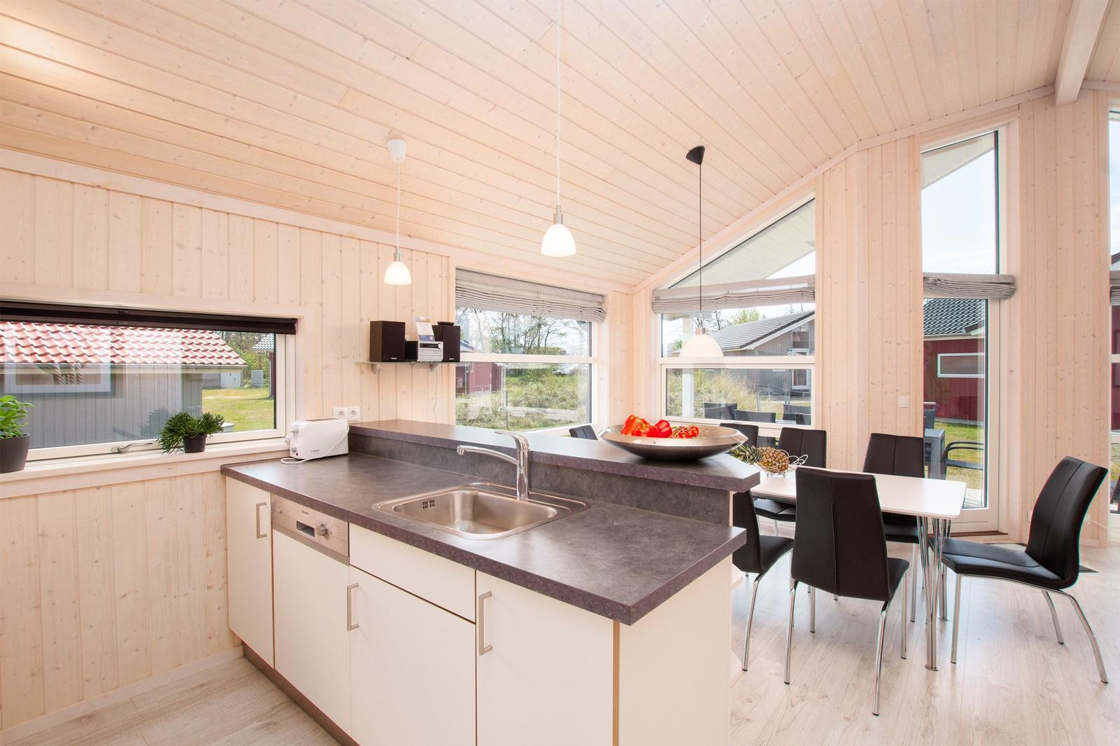 Küche mit Essbereich, Holzwände und großzügigen Fenstern.