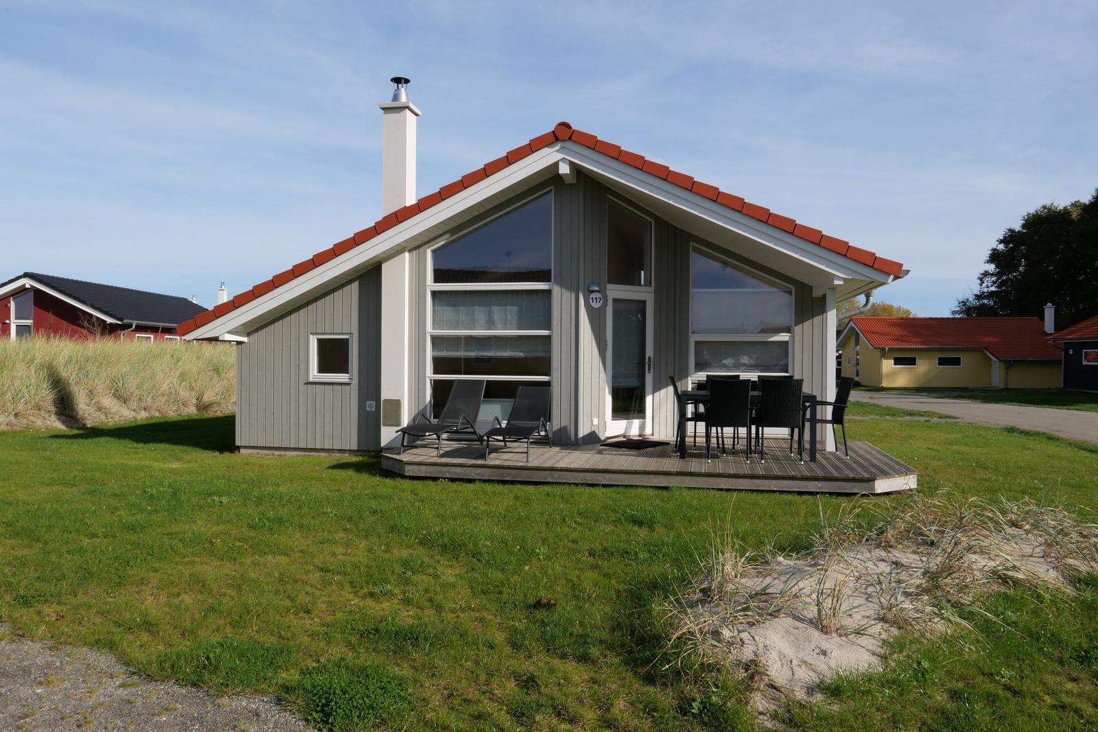 Moderne Ferienhaus mit Terrasse, Garten und rotem Dach.