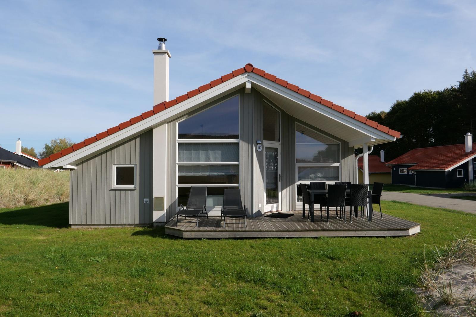 Modernes Ferienhaus mit Holzterrasse, Sitzgelegenheiten und rotem Dachziegel