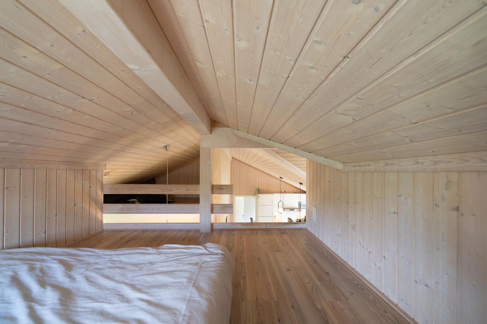 Schlafzimmer mit Holzdecke und Blick in die Küche