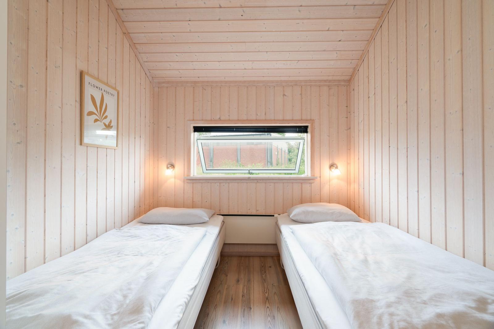 Zwei Betten in einem holzverkleideten Raum mit Fenster und Wandbild.