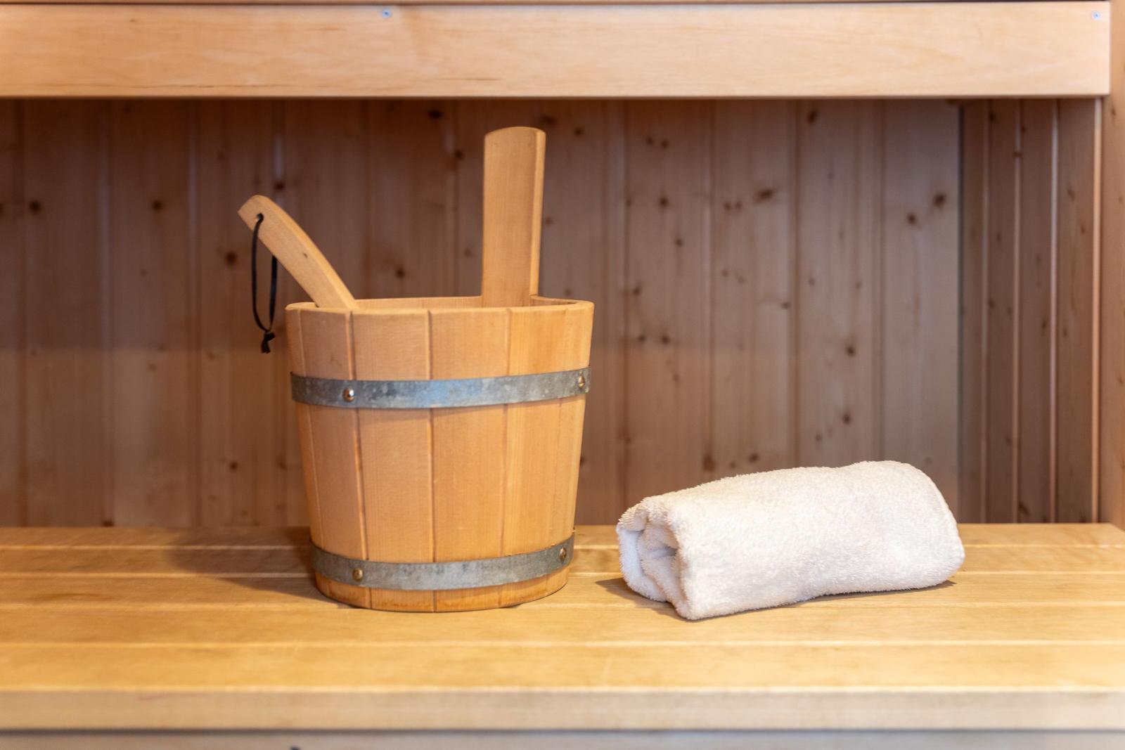 Holzbadewanne mit Eimer und Handtuch auf Holzboden