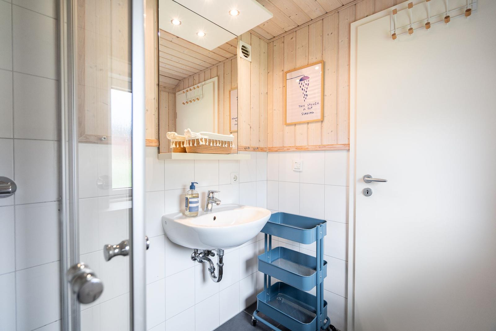 Badezimmer mit Dusche, Waschbecken und blauem Wagen.