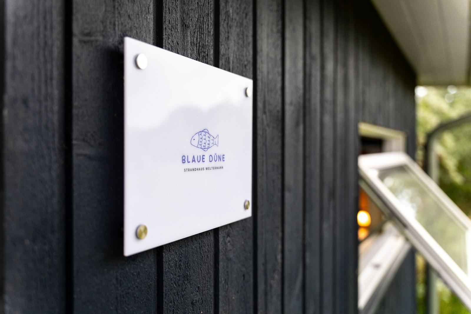 Schild an der Fassade zeigt den Namen Blaue Düne Strandhaus Weltermann.