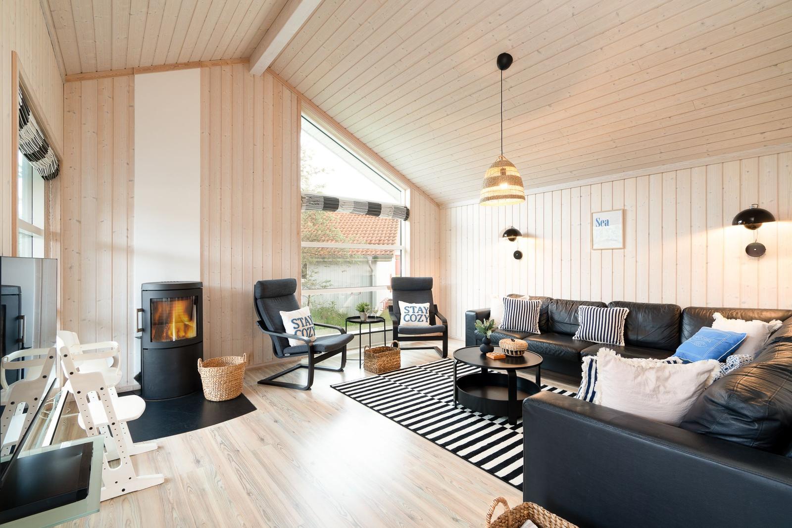 Wohnzimmer mit Holzwand, Kamin, Sofa und Sessel.