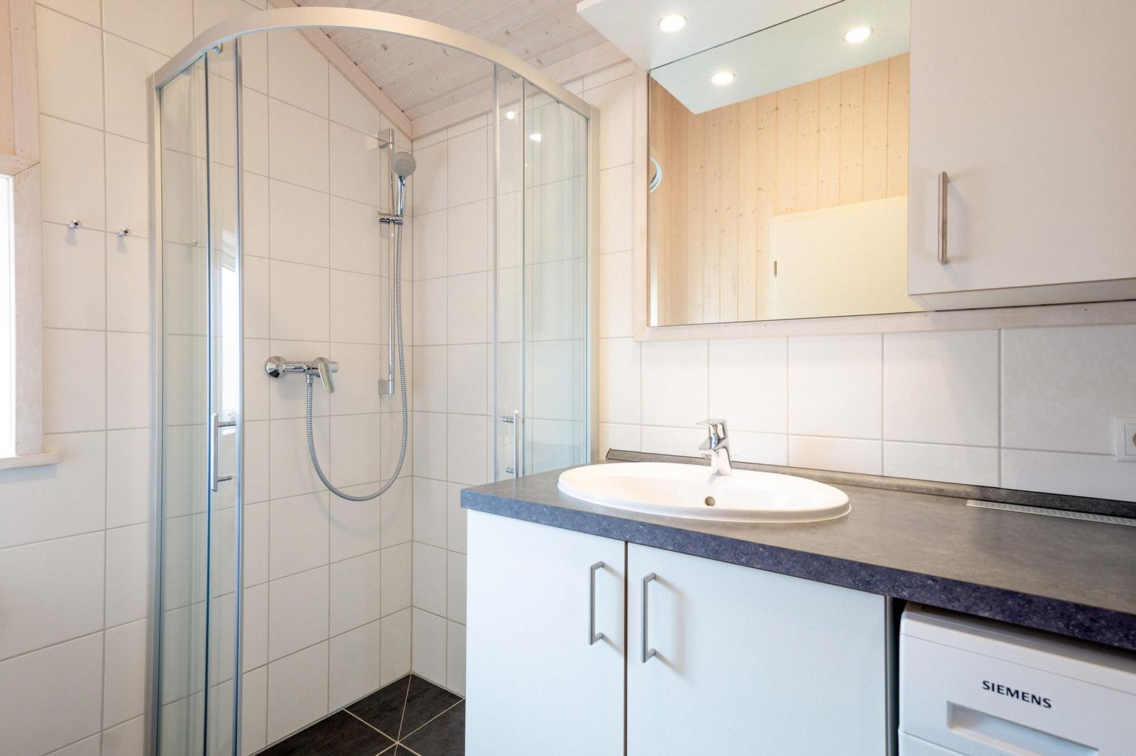 Badezimmer mit Dusche, Waschbecken und Spiegel