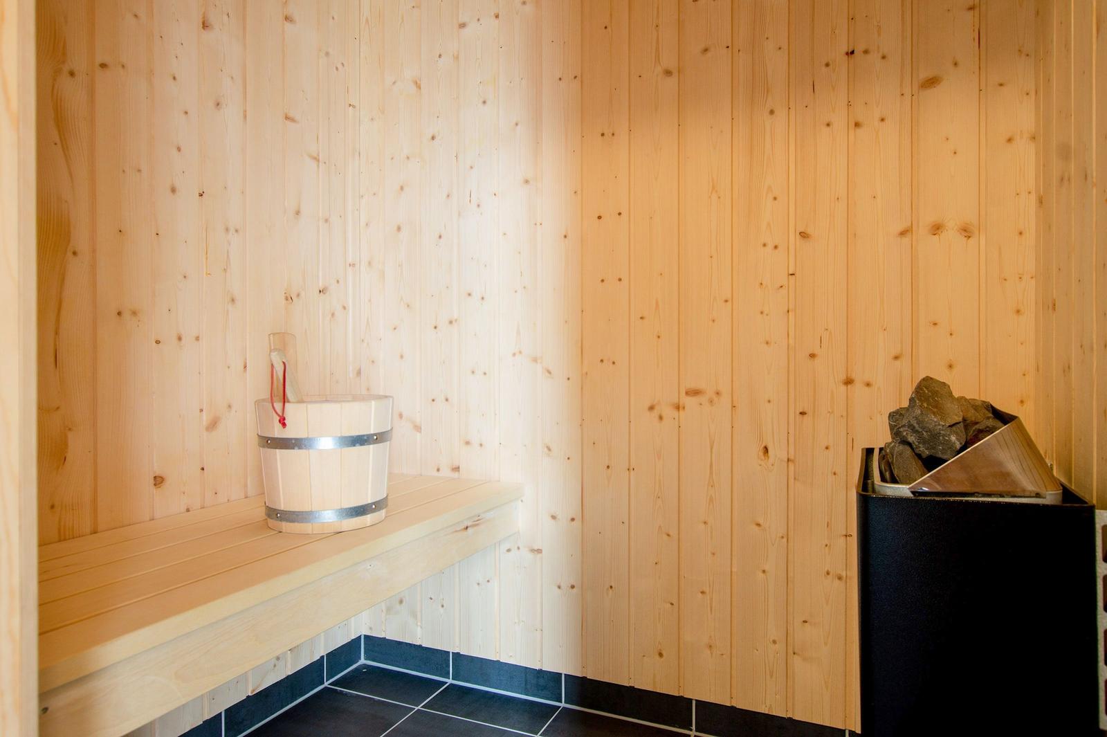 Sauna mit Holzwand, Sitzbank, Eimer und Holzstapel