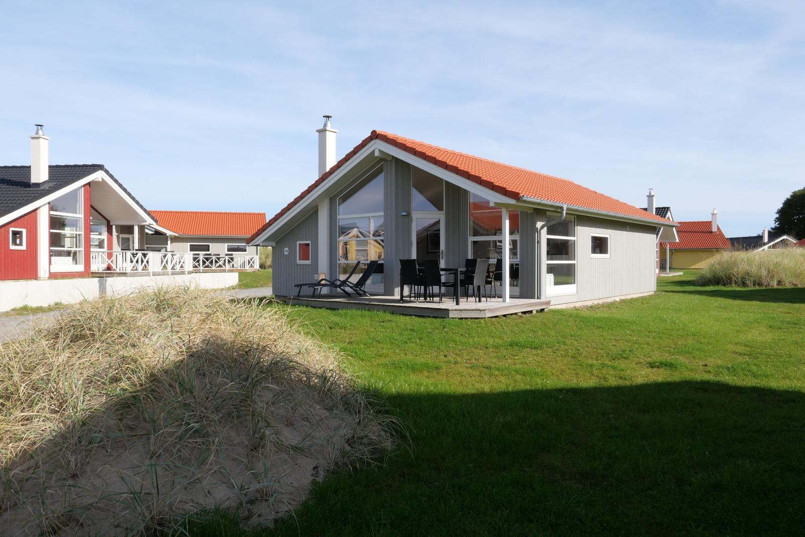 Moderne Villa mit Terrasse, Garten und rotem Dach. Sicht auf Nachbarhäuser.