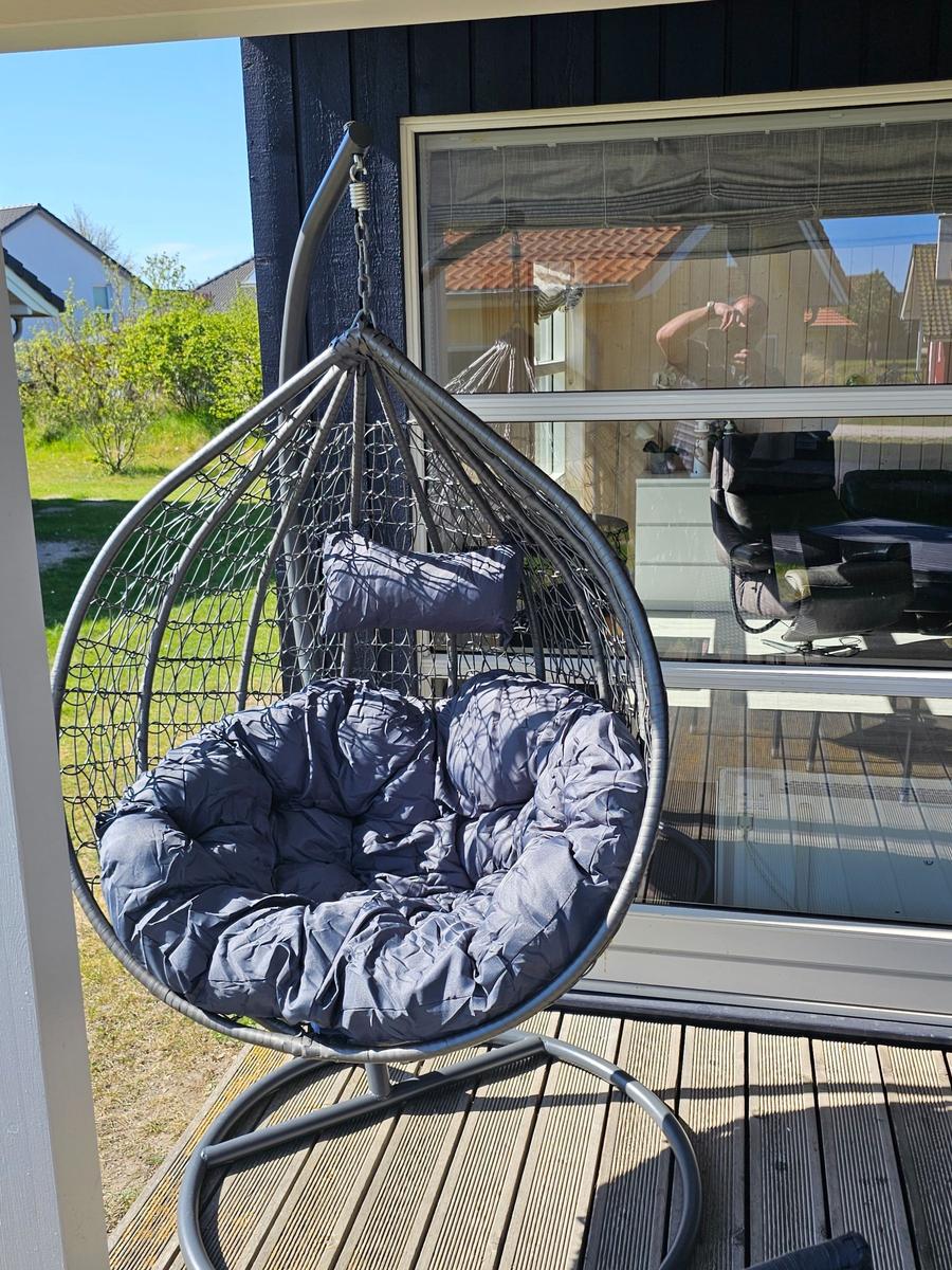 Hängesessel mit Kissen auf Terrasse vor Haus mit Fenster