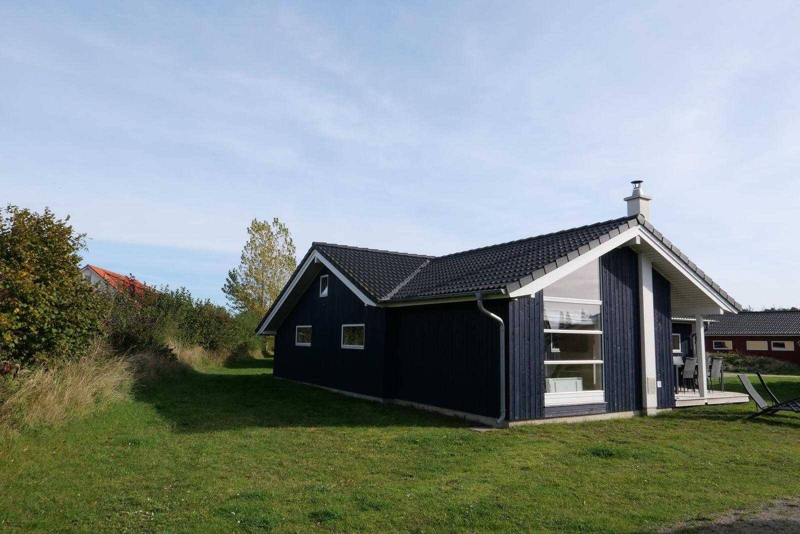 Ein dunkelblaues Haus mit weißen Akzenten und einer Terrasse im Freien.