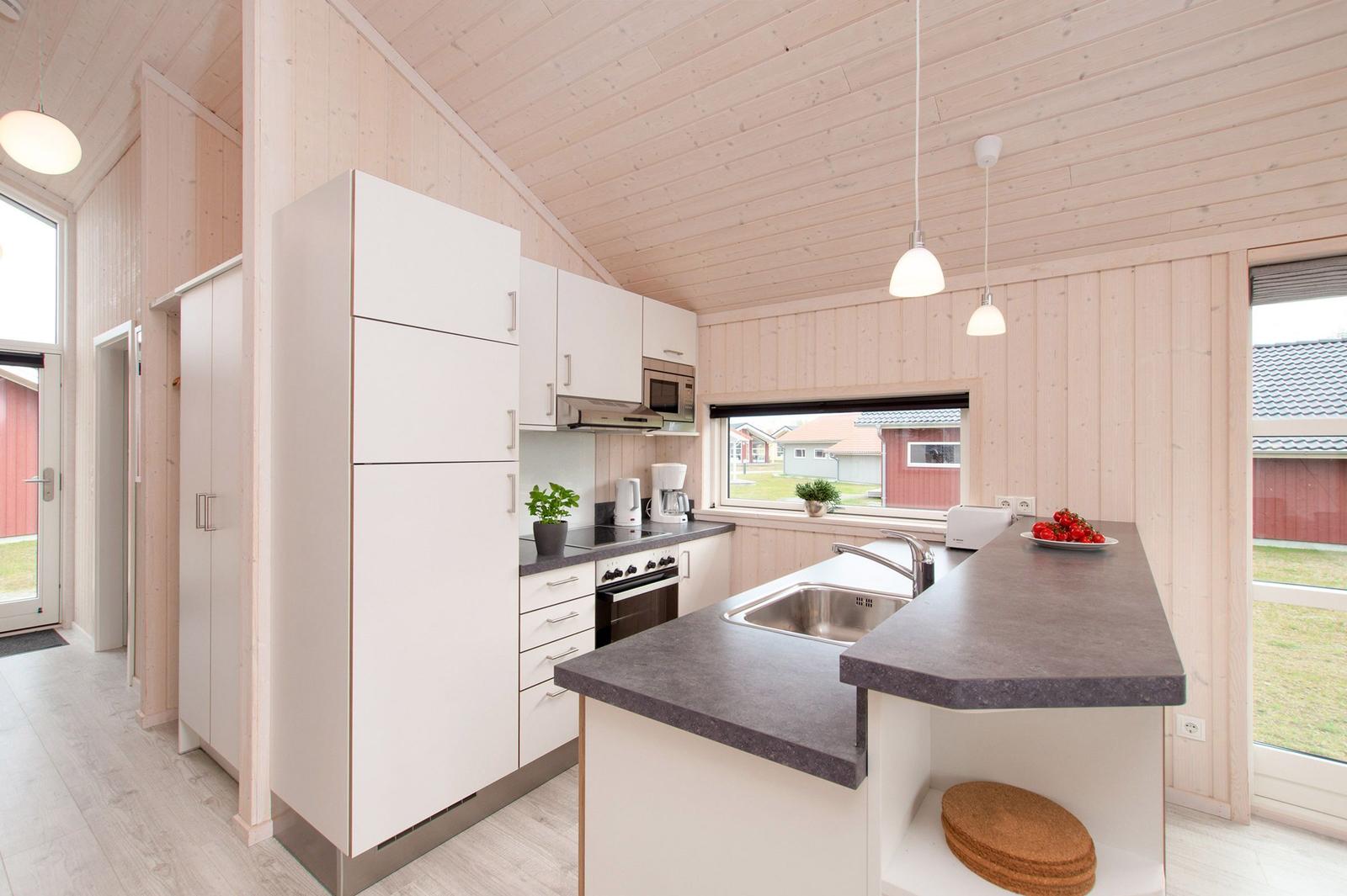 Moderne Küche mit weißer Einbauküche, dunklem Arbeitsplatz und Holzwandverkleidung.
