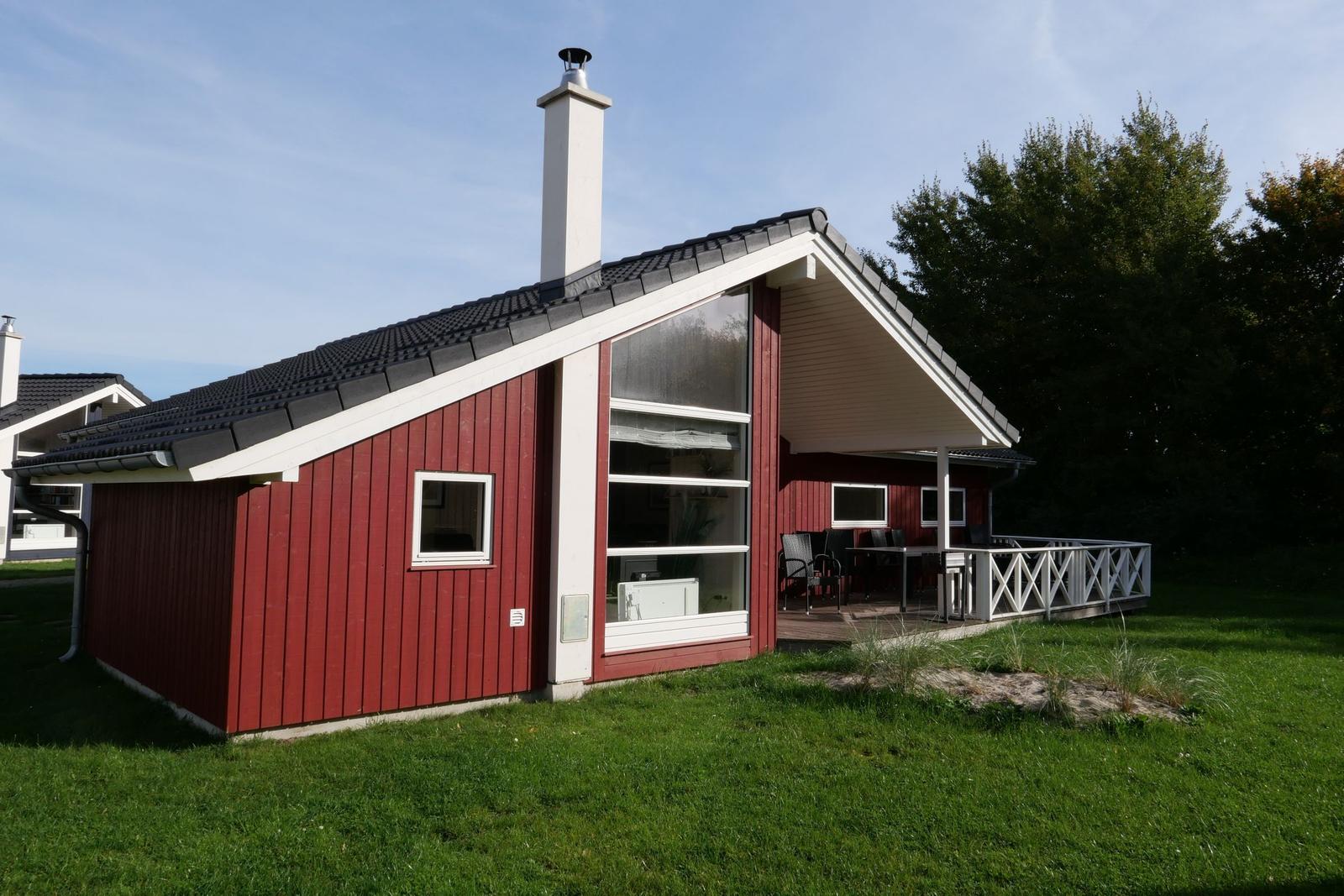 Rotes Holzhaus mit Terrasse und Grillplatz im Grünen